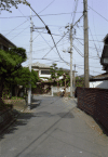 A nice and quiet place in the labyrinth of small streets in Tsujido, there is someone riding a bike, nice trees and lots of wires.