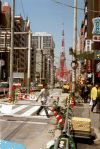 Tokyo Tower seens from one of the main streets, with people, cars, road works